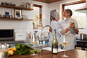 Fall in love all over again. a happy mature couple dancing together while cooking in the kitchen at home.