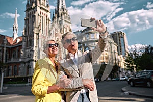 Fall in love. Happy and cheerful mature caucasian couple in sunglasses taking selfie by mobile phone and smiling while