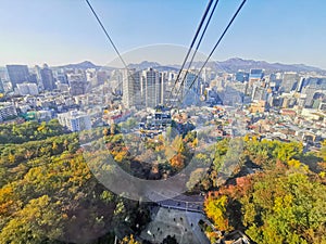 Fall maple leaves foliage Autumn with city apartments scene and cable car tower in Seoul, South Korea