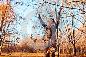 Fall. Middle-aged woman throwing leaves in autumn forest. Senior woman having fun outdoors