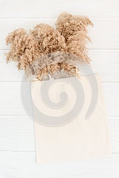 Fall mockup with tote bag blank and dry reeds on white wood background