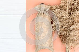 Fall mockup with wine bag blank and dry reeds on white wood background.