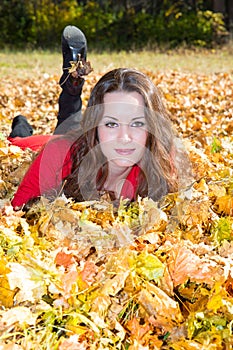 Fall. Portrait of beautiful young woman in autumn park with leaves