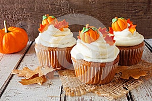 Fall pumpkin spice cupcakes with creamy frosting close up against rustic wood