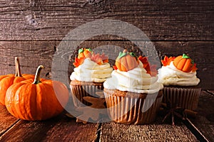 Fall pumpkin spice cupcakes with creamy frosting close up against wood