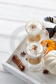 Fall pumpkin spice latte with whipped cream on white wooden background