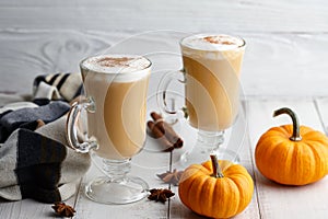 Fall pumpkin spice latte with whipped cream on white wooden background