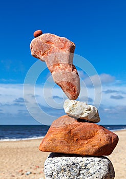 The fall of the pyramid of balanced stones on blue sky background. The concept of fall risk and unstable equilibrium