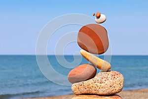 The fall of the pyramid of balanced stones on blue sky background. The concept of fall risk and unstable equilibrium