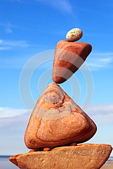 The fall of the pyramid of balanced stones on blue sky background. The concept of fall risk and unstable equilibrium