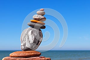 The fall of the pyramid of balanced stones on blue sky background