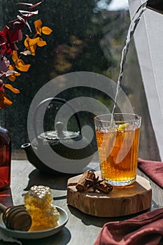 Fall season steaming hot tea with lemon, autumn leaves, honeycomb, wooden