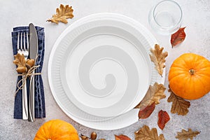 Fall season table setting with pumpkins, leaves and cutlery