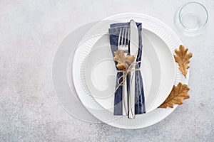 Fall season table setting with white plate and decorated cutlery