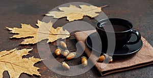 Fall still life with a cup of coffee, dry leaves and acorns on a brown background. Acorn coffee. A substitute for coffee