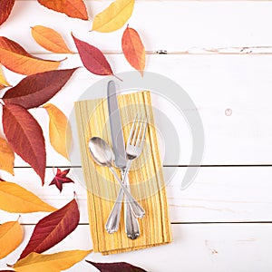 Fall Table Place Setting Invite Card with Brown and Gold Leaves, Silverware, and Napkin Flat Lay on White Shiplap boards backgrou