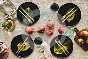 Fall table setting with black dinnerware and cutlery, top view