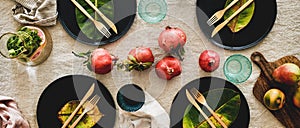 Fall table setting with black dinnerware and cutlery, wide composition