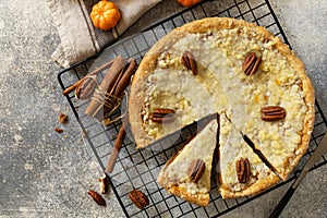 Fall traditional pie pumpkin with crumble and pecan on a gray stone background. Thanksgiving dessert. View from above. Copy space