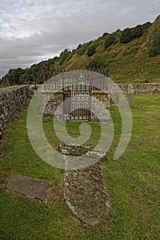 fallen and half buried Gravestone in front of a Burial Enclosure at the Nether kirk yard Burial Ground at the foot of the Cliffs. photo