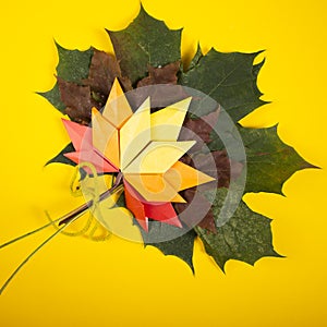 Fallen handmade leaves autumn concept traditional paper craft art origami topshot on yellow background