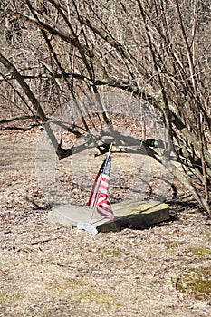 Fallen headstone with small American flag and Veteren memorial plaque