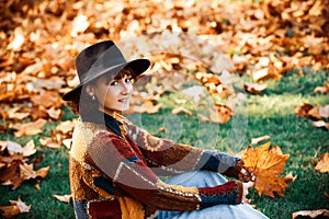 Fallen leaf on the background of green grass. Portrait of beautiful young woman walking outdoors in autumn. Autumn