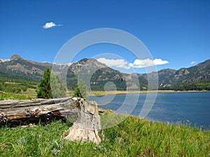 Fallen log by a Colorado lake and mountains.