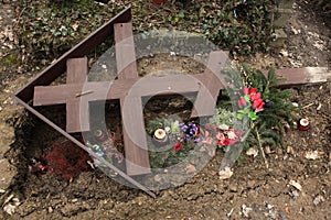 Fallen orthodox cross on an unmarked grave. photo