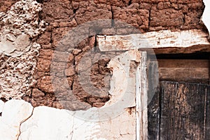 Fallen plaster on old adobe brick wall with wooden lintel in a rural house