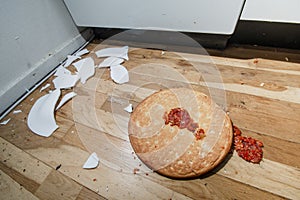 Fallen and shatter plate with food in kitchen
