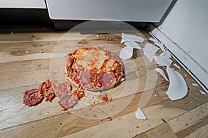 Fallen and shatter plate with food in kitchen