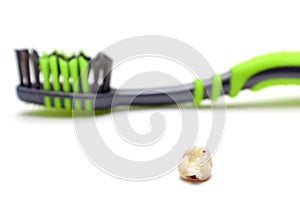 A fallen sick baby tooth and a toothbrush on a white background. The concept of diseases of teeth and gums, caries, periodontal