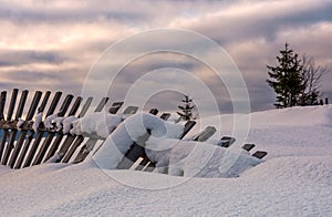 Fallen wooden fence on snowy hillside