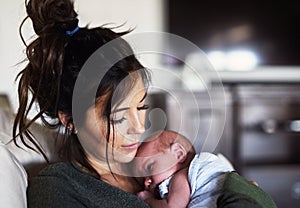 Falling asleep in moms arms. A cheerful young woman holding her little infant son at home during the day.