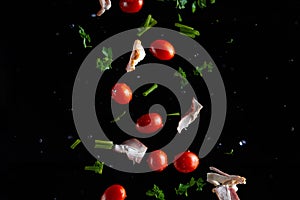 Falling bacon, cherry tomatoes, parsley on a black background with water drops, freeze in motion, cooking and recipe books, banner