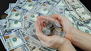 Falling coins in hands. Old coins fall into female hands against money background with one hundred US dollars banknotes. Coins are