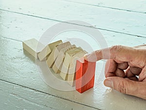 Falling domino concept and hand stops it. Crisis solution.