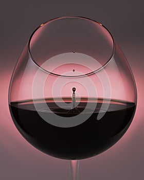 A falling drop of red wine in a glass, close-up