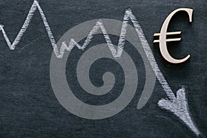 Falling euro currency rate.Euro inflation.Euro sign and a down arrow on a black background. Financial Crisis.European
