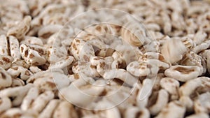 Falling flakes of puffed wheat spelt in slow motion, close-up