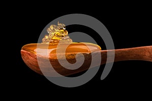 Falling and flowing honey on a wooden spoon isolated on black with clipping path