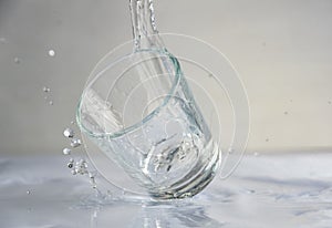 Falling, flying or standing glass with a clear liquid intended for vodka and splash of liquid