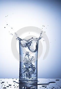 Falling ice cubes in a glass of water with splash