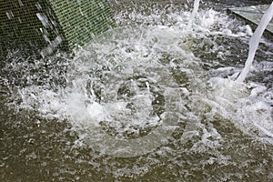 Falling jet fountain in bowl water on bright sunny day, creating movement water in bowl, waves, spray, foam.