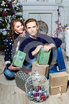 Falling in love boy and girl sitting near the Christmas tree i