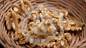 Falling nutritious raw shelled walnuts into a rattan kitchen bowl in slow motion.