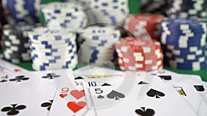 Falling playing cards and casino chips on green table