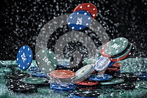 Falling poker playing chips on a green table and black background under the water drops. Online gambling. Addiction.