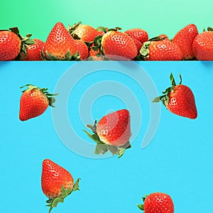 Falling ripe juicy strawberries on a blue background